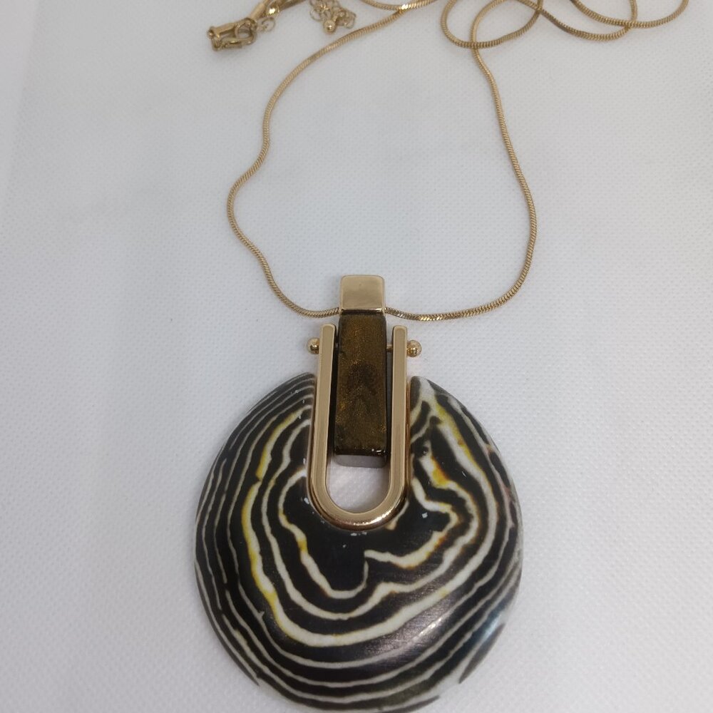 A large modern medallion necklace with a gold chain and trim.